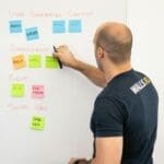 a man with sticky notes by a whiteboard